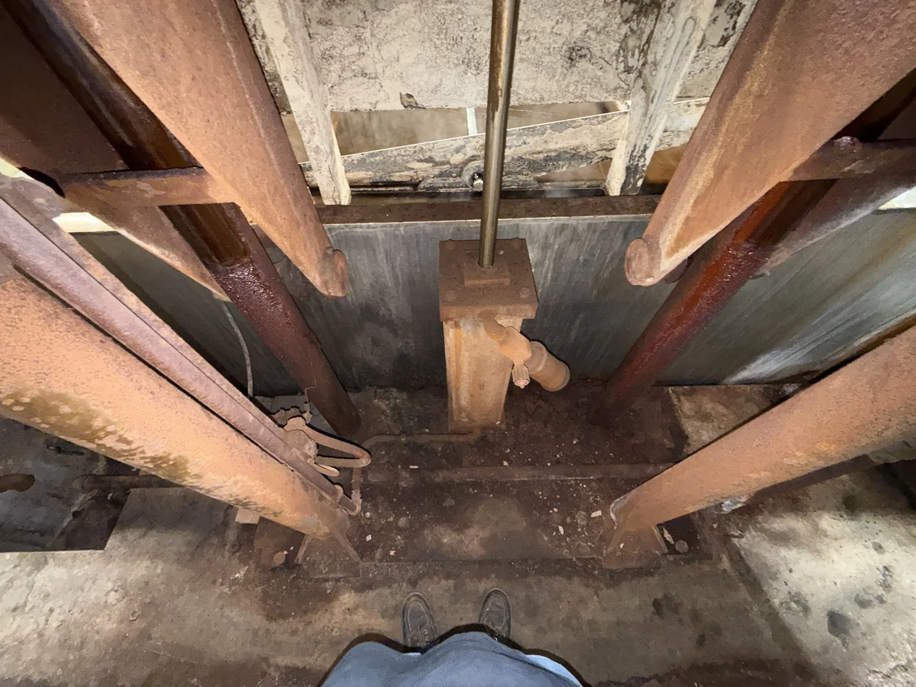 Looking down into the cleaning bath from the back of the agitation machine, between the heavy steel rocking arms toward the drive block at the centre.