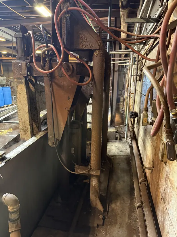 Side view of the agitation machine showing the long steel frame running beside the bath, with hoses overhead.