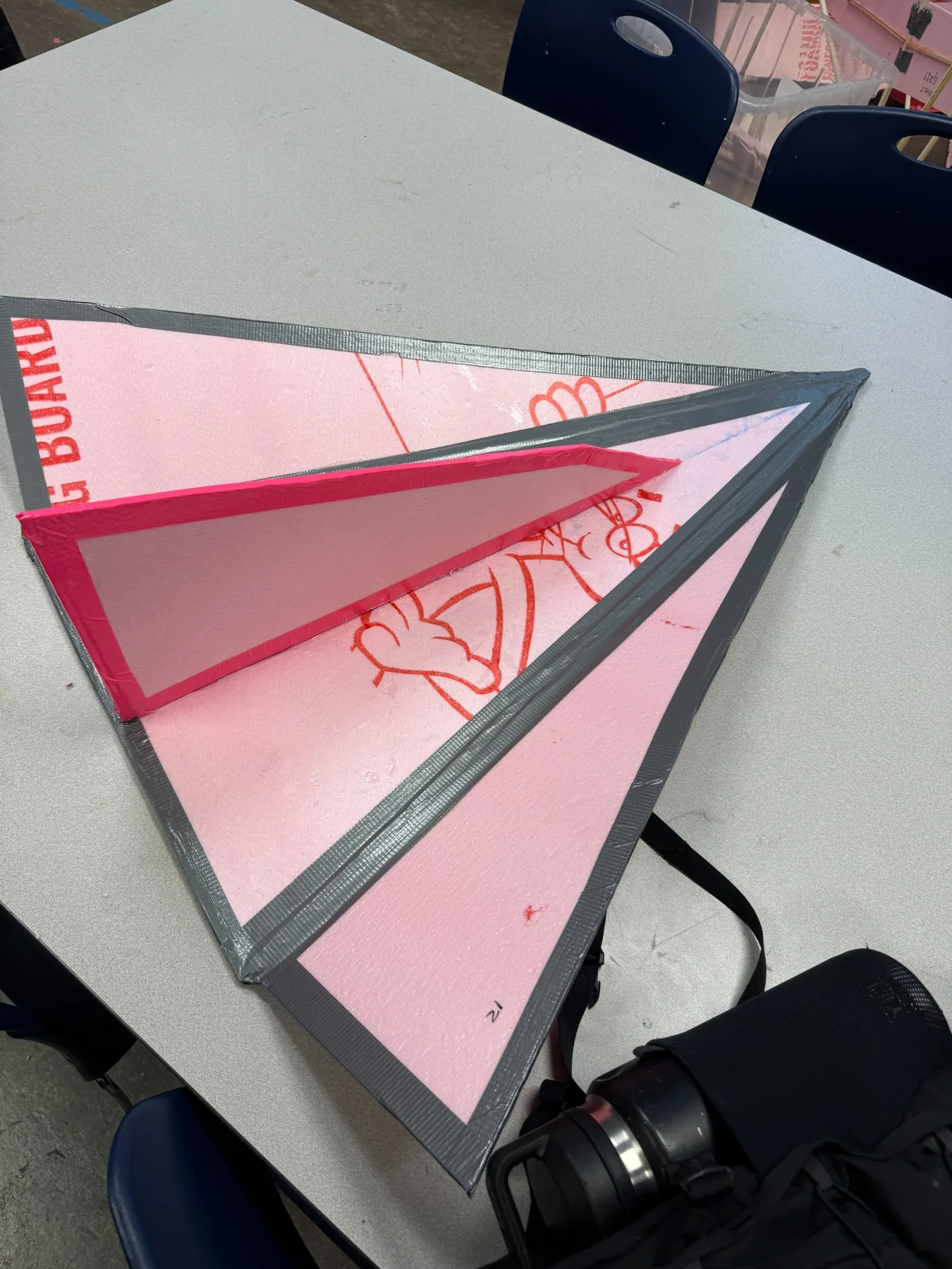 The fabricated glider prototype resting on a table, showing its triangular delta planform with reinforced taped edges and a raised centre member.