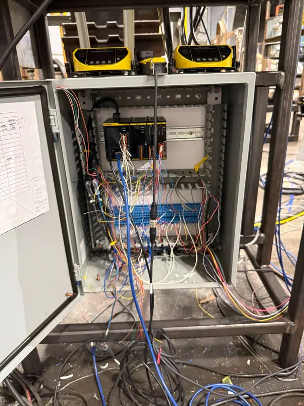 Open control cabinet showing a controller, terminal blocks, and bundled field wiring routed out of the enclosure.