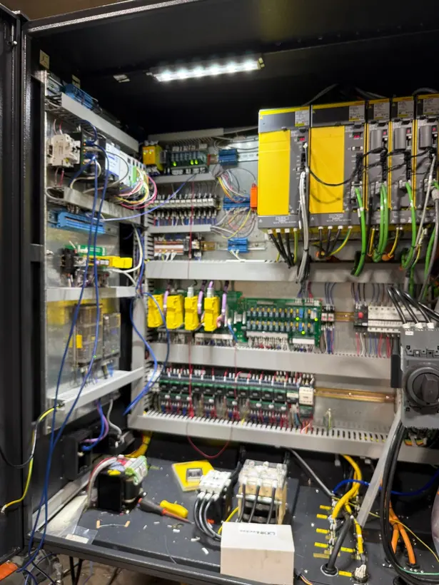 Machine tool control cabinet with drives, relays, terminal rails, and colour-coded wiring looms.