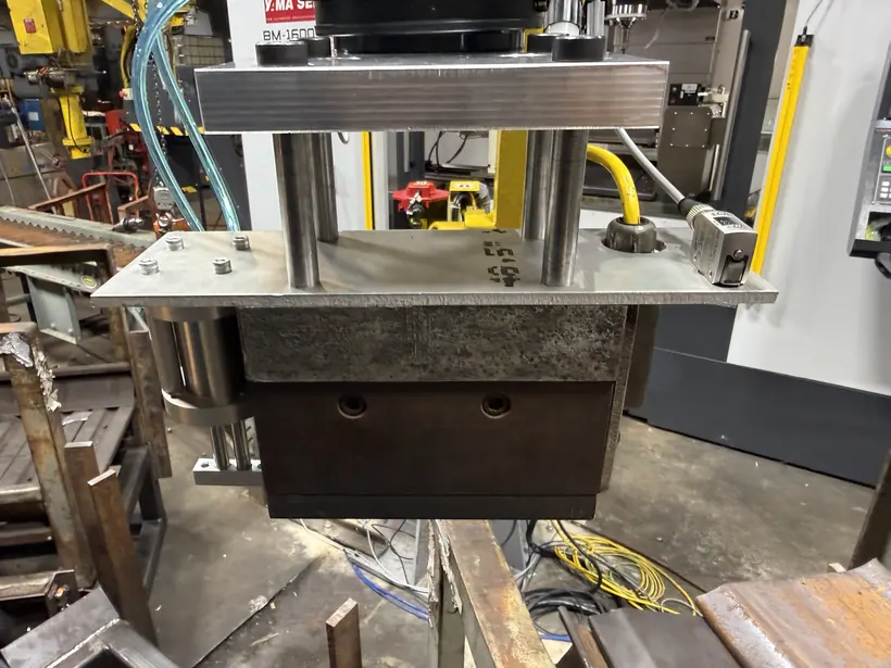 Modified end-of-arm tooling mounted on the robot, with the plate supported on two posts above the magnet body.