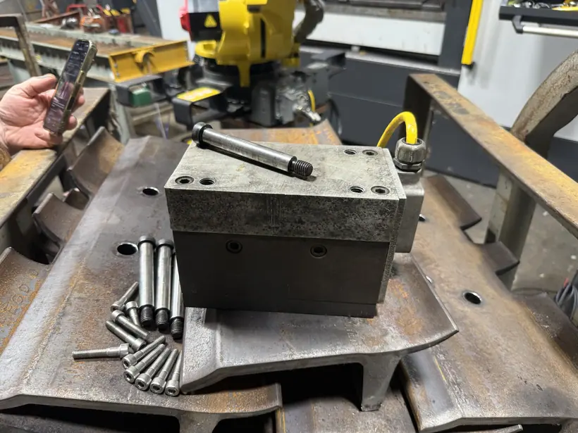 Original magnet block resting on a steel track shoe with dowel pins laid out beside it.